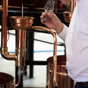 Pierre Solignac dégustant un petit verre de vodka devant un équipement de brassage en cuivre