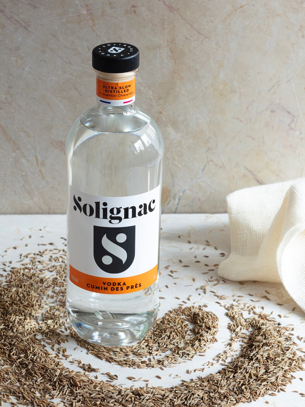 Bottle of Solignac vodka with herbs on a light surface, Vodka cumin des pres by Maison Solignac