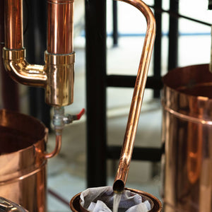 Copper vodka apparatus with a filter and liquid being poured.